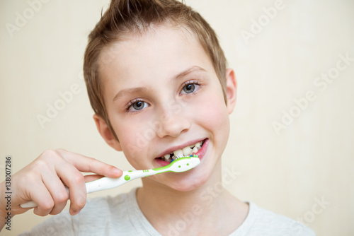 Cute boy brushing his teeth. Light background
