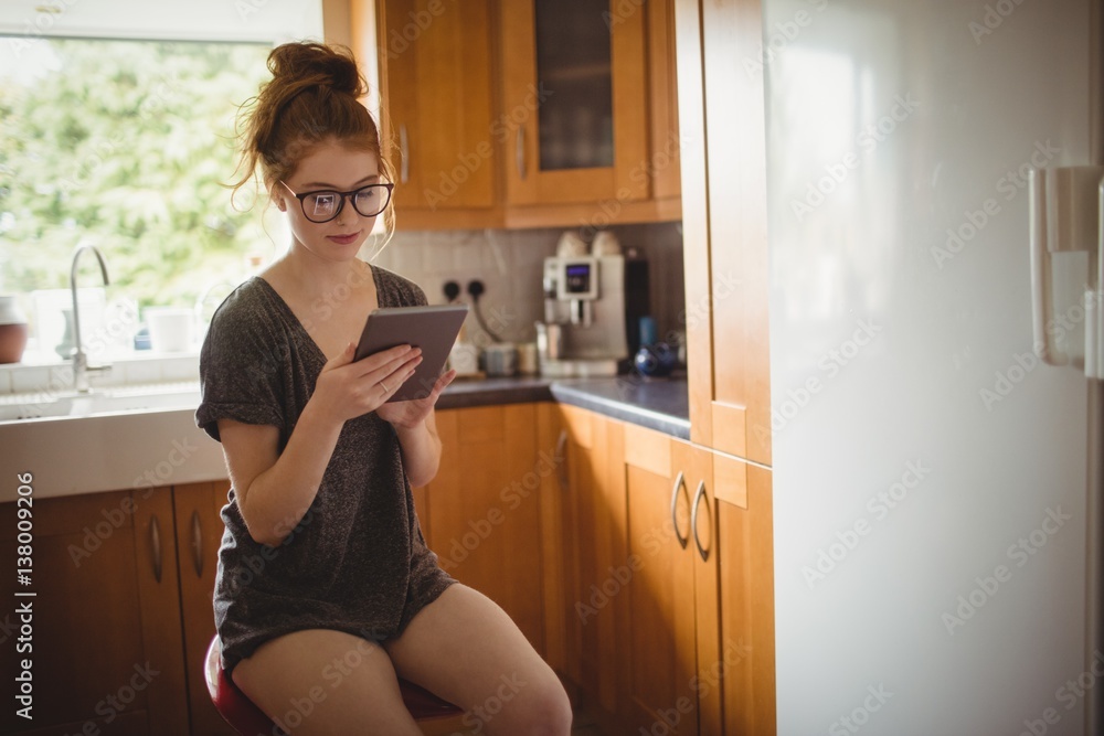 Woman using digital tablet in kitchen at home Woman using digital tablet in kitchen at home