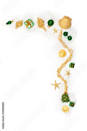Border of green ornaments and shells painted gold on white sand
