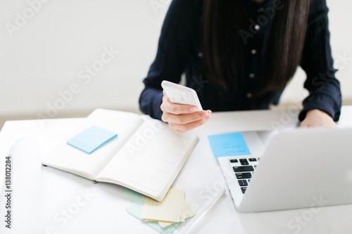 Business woman checking her text messages while at her computer