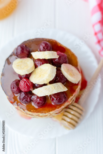 Healthy breakfast. Stack of delicious  homemade pancakes with honey  cherry and banana on white plate 