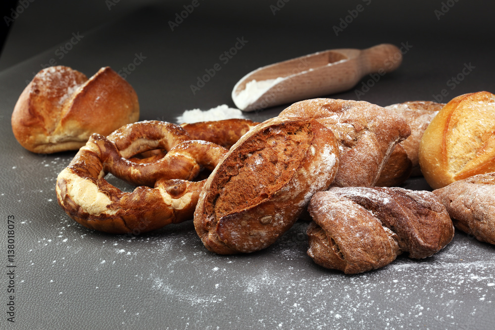 Different kinds of bread and bread rolls on board from above. Kitchen or bakery poster design.