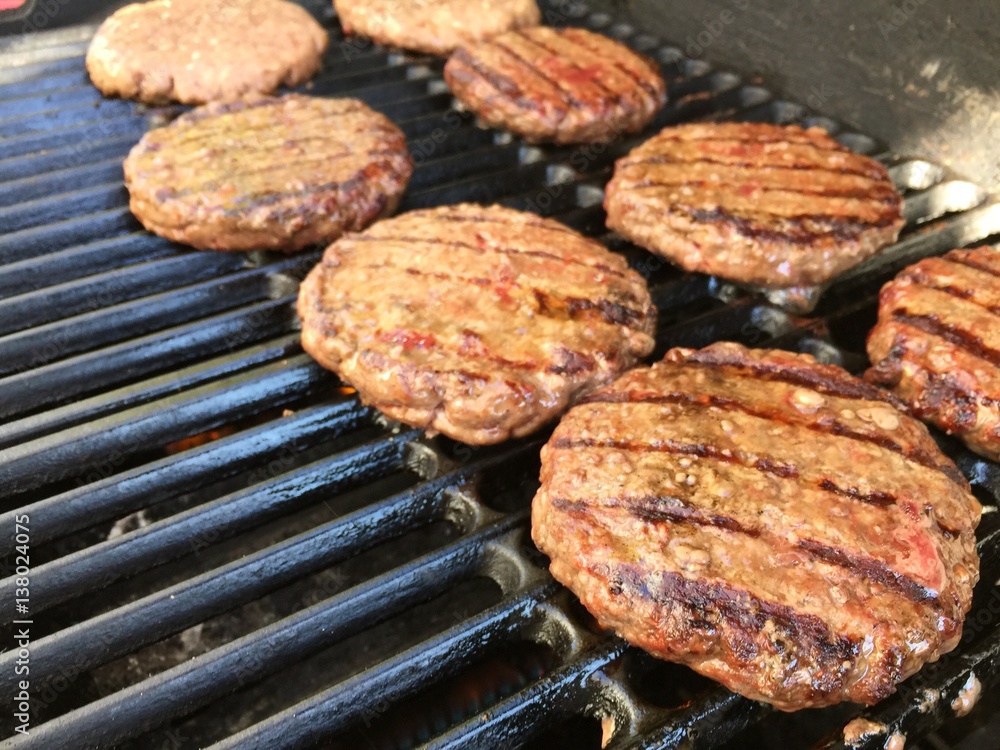 fresh Angus beef hamburgers grilling on the barbecue.