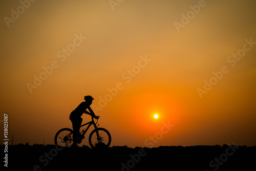 Silhouette of young man cyclist on sunset.