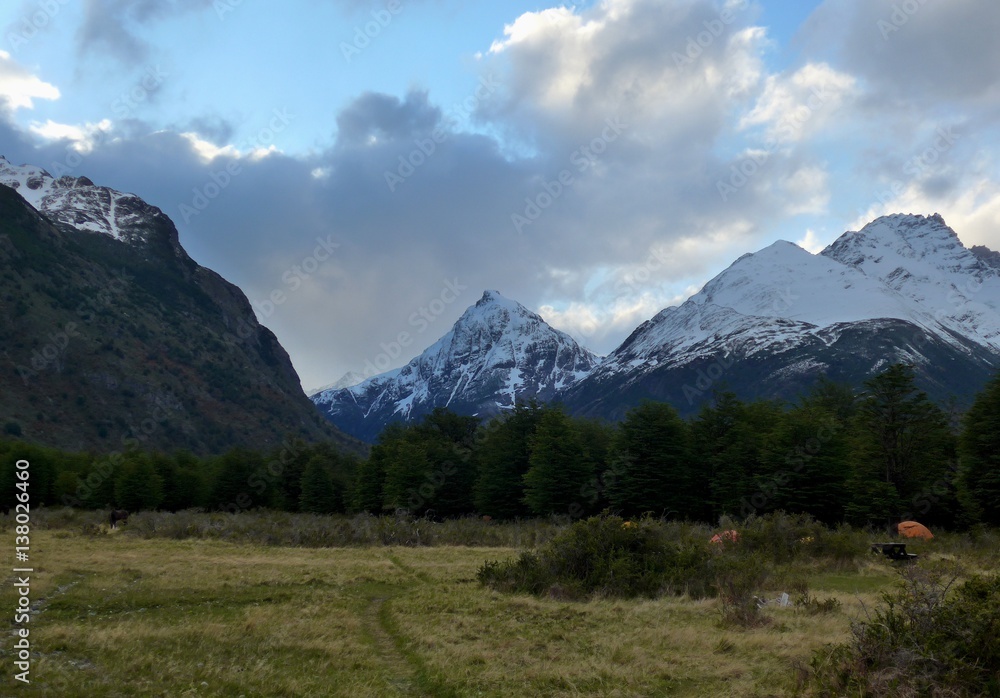 Beautiful meadow and campsite at Refugio Dickson surrounded by snow capped mountains in Torres del Paine National Park.