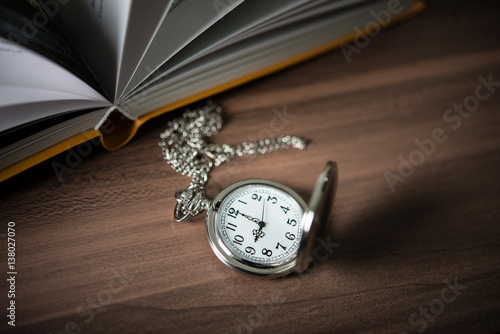Close up of golden pocket watch lean on pile of book.