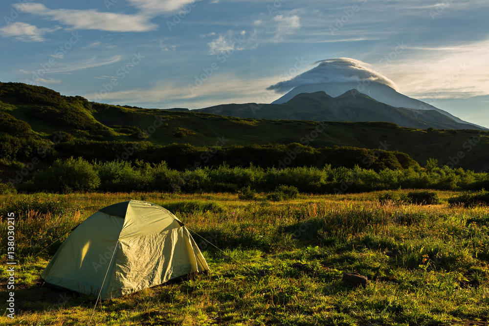 Tourist tent on a background of Vilyuchinsky stratovolcano at dawn. View from brookvalley Spokoyny at the foot of outer north-eastern slope of caldera volcano Gorely.