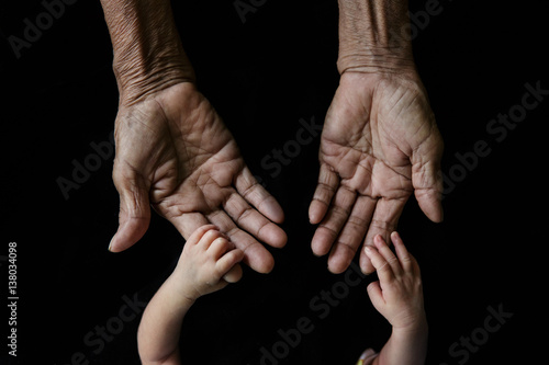 Hand of a young baby touching old hand of the elderly (Soft focus and blurry)