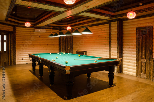 Photography room billiards decorated in dark wood with low lamps, billiard table with green