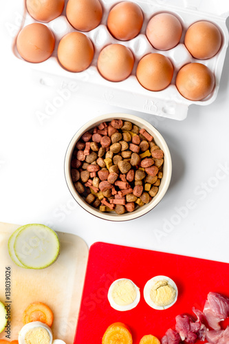 food for pets with meat and eggs on kitchen background top view
