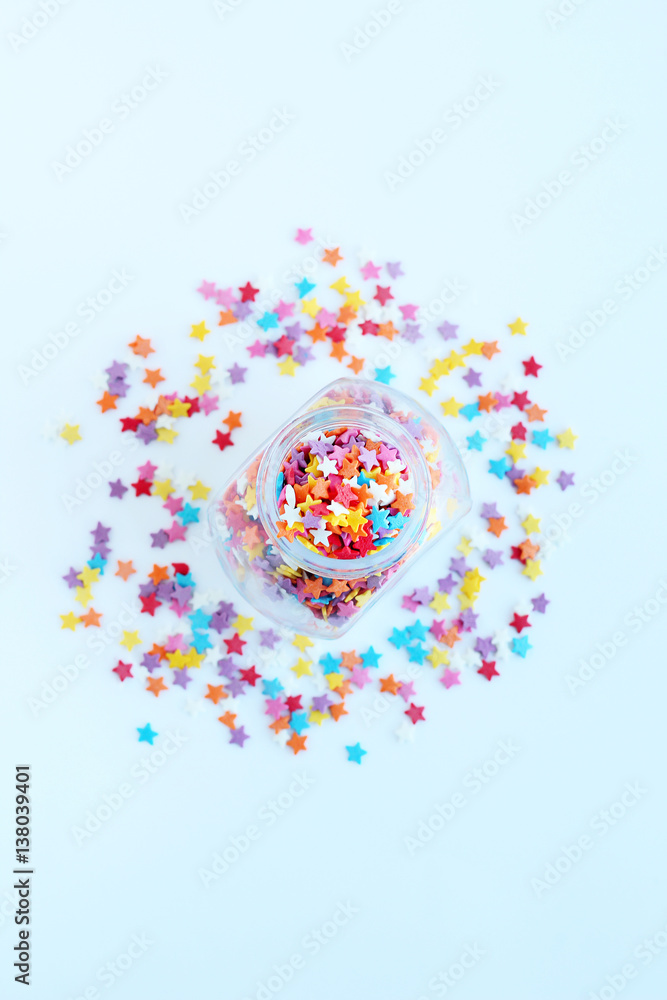 bright colored confectionery sprinkling of stars in a glass jar on a light background. soft focus, blur bright colored confectionery sprinkling of stars in a glass jar on a light background. soft focus, blur