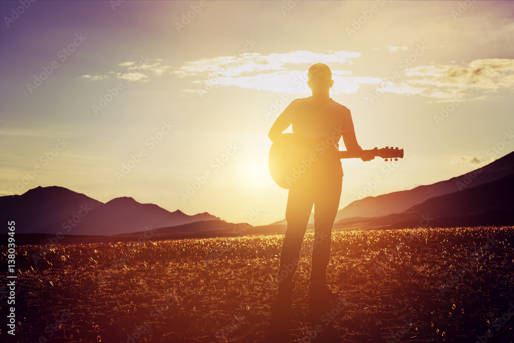 Naklejka premium Man guitar sunset mountains concept