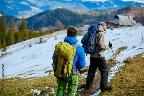 two hikers with backpack on the trail in the Carpathians mountains at winter. hikers stands on the cloudy sky background