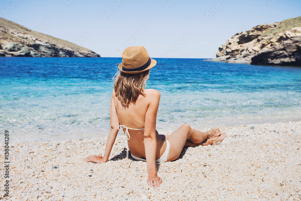 Young woman sitting on the beach and having fun. Vacations lifestyle concept