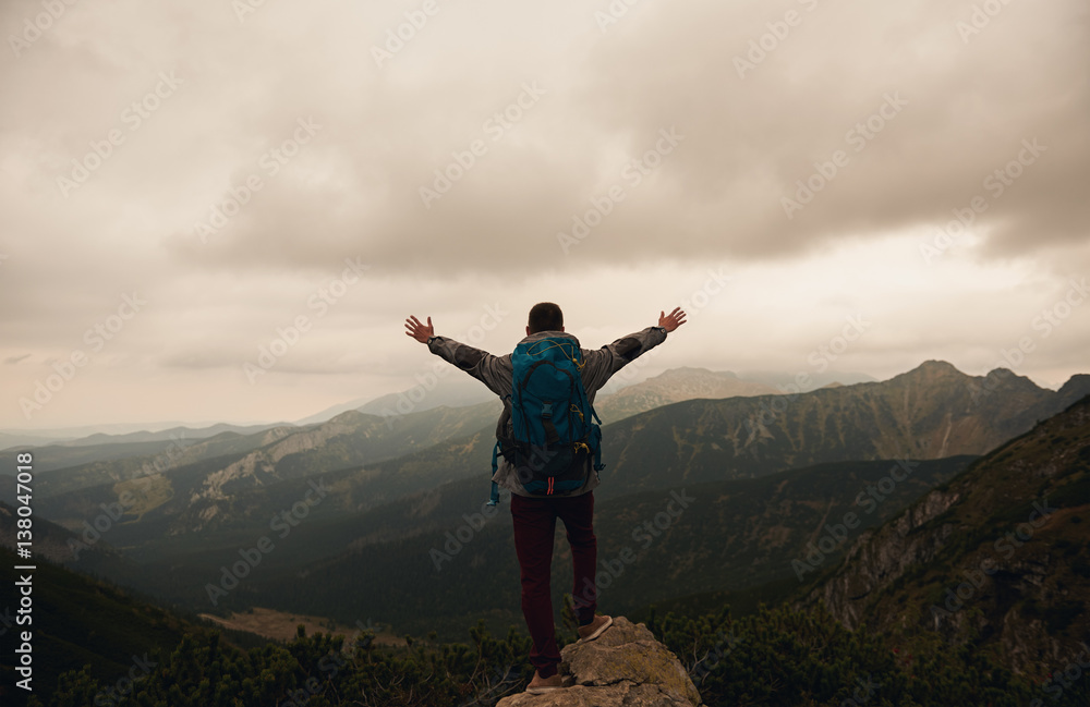 Hiker standing on a mountain with arms raised skyward Hiker standing on a mountain with arms raised skyward