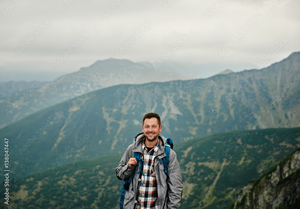 Smiling hiker standing against a mountain landscape
