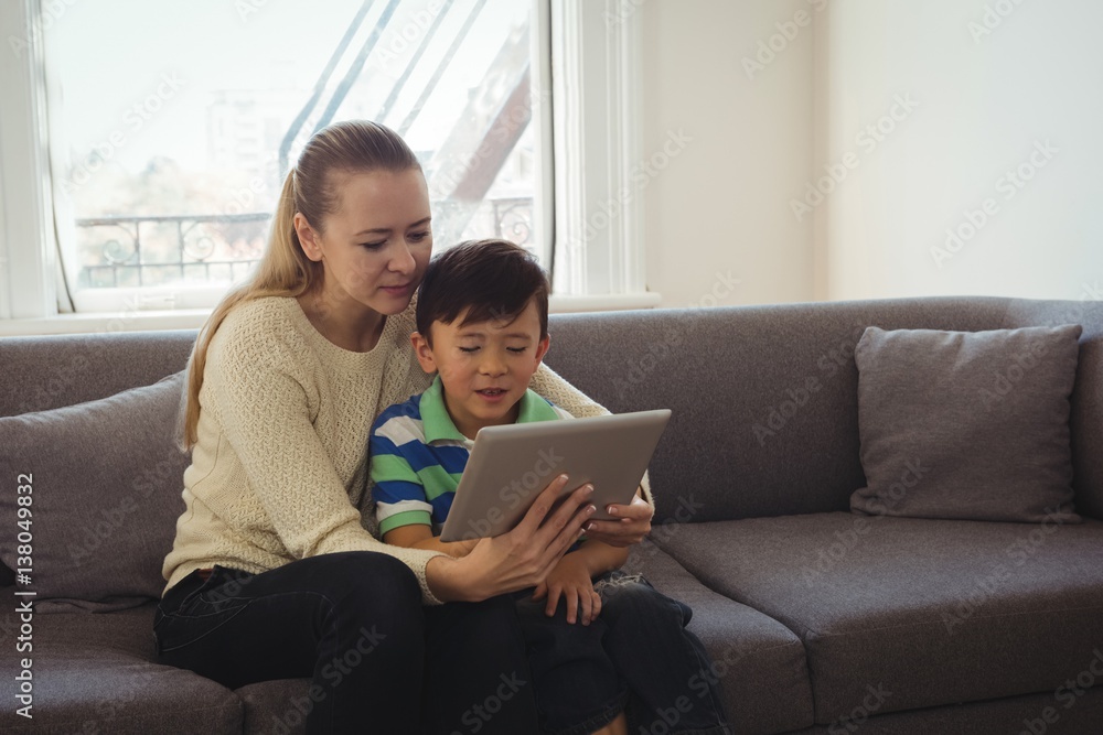 Mother and son using digital tablet in living room Mother and son using digital tablet in living room