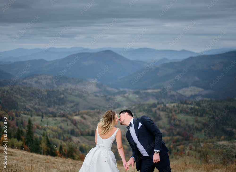 A moment before a kiss betweeen wedding couple standing on the mountain hill
