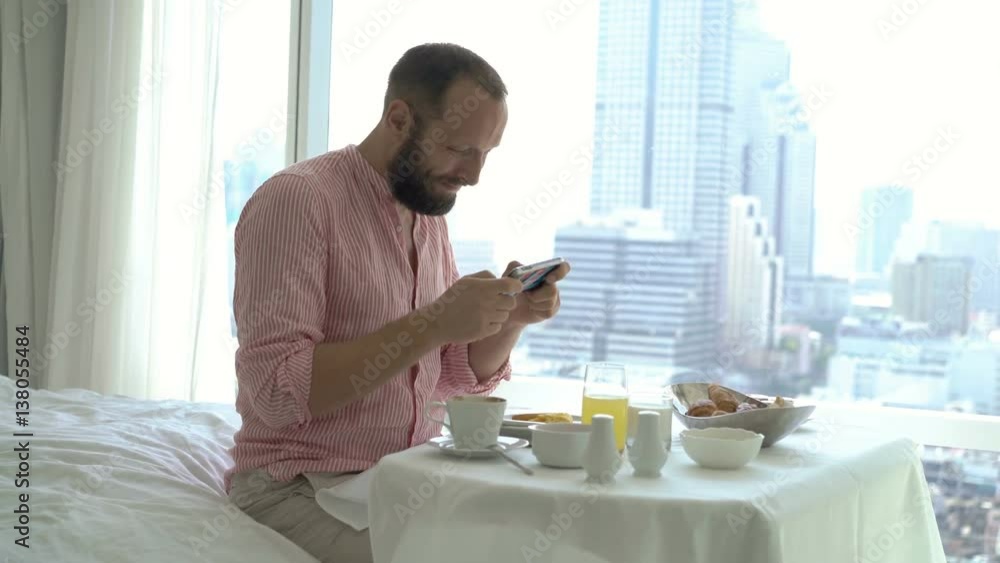 Man playing game on smartphone during breakfast sitting on bed at home
Man playing game on smartphone during breakfast sitting on bed at home