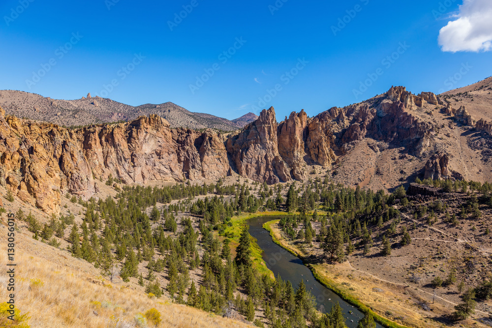 Amazing landscape. The river flows between rocks. Beautiful rocks in the foreground. Colorful valley between the mountains. High mountains on the horizon. Smith Rock state park, Oregon