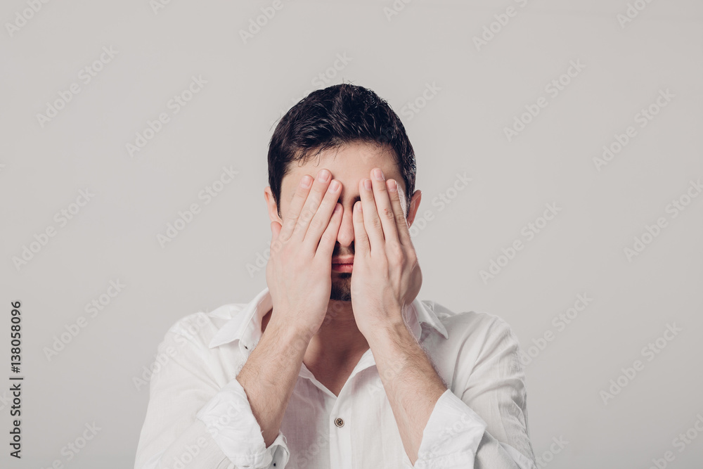 portrait of man in white shirt closes his eyes with hands on gr portrait of man in white shirt closes his eyes with hands on gr