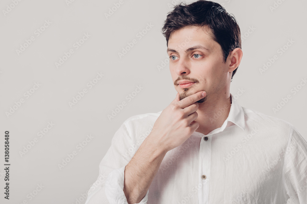 portrait of handsome young pensive man in white shirt on gray ba portrait of handsome young pensive man in white shirt on gray ba