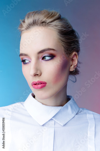 beautiful young woman with bright makeup in white clothing posing on colorful background