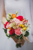 beautiful wedding bouquet of bright assorted colors of roses, eustoma carnations on the hand of the bride close-up
