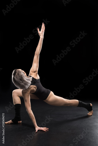 Young athletic woman contemporary dancer posing on black