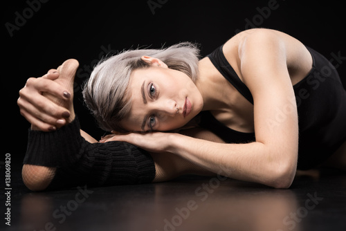 Attractive sporty young woman dancer stretching and looking at camera