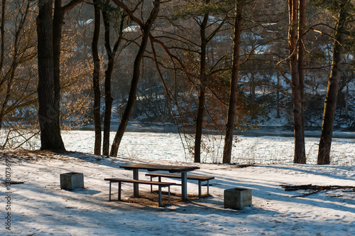 Bench and table in the forest near the river. Winter time.