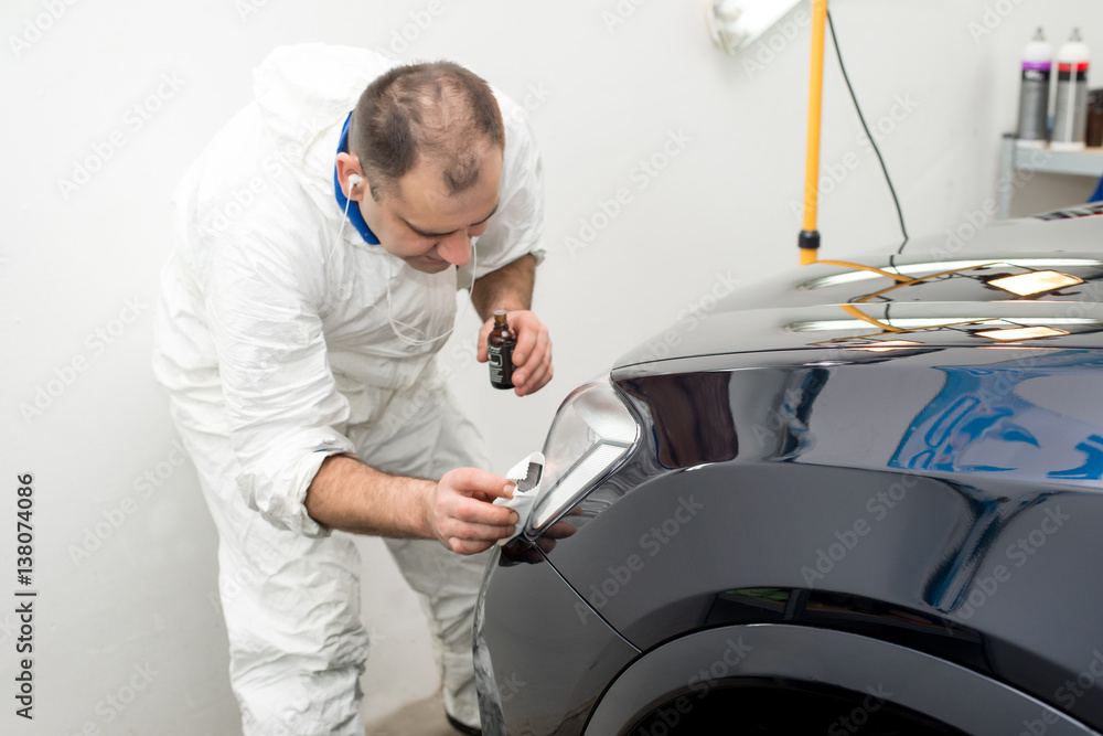 Obraz premium Man on a car wash polishing car with a polish machine