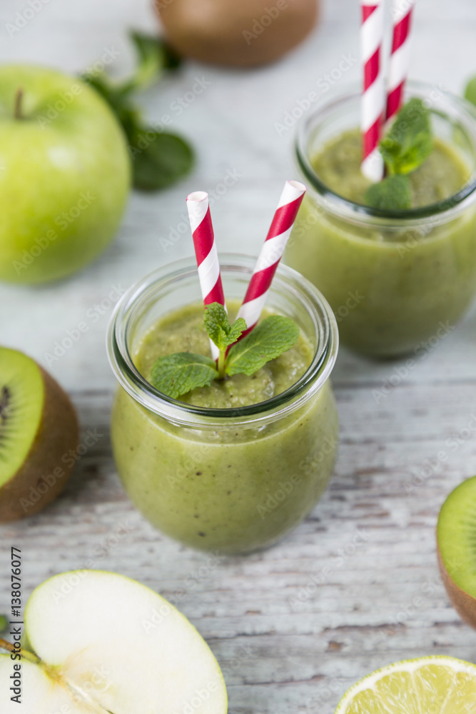 Glass of green smoothie and ingredients on wood Glass of green smoothie and ingredients on wood