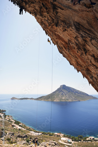 Greece, Kalymnos, climber abseiling in rock wall photo