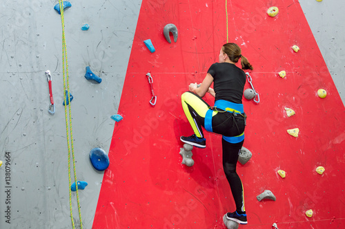 Athletic woman climbing indoors, view from the back