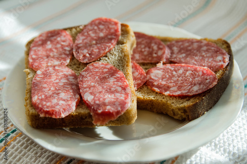 sandwiches of black bread with smoked sausage lies on a plate