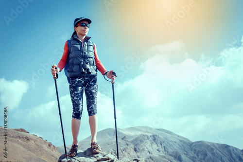 Hiker with backpack relaxing on top of a mountain and enjoying valley view during sunrise