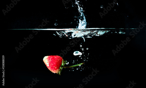 Strawberry falling in water isolated against a black background,Strawberry falling in water