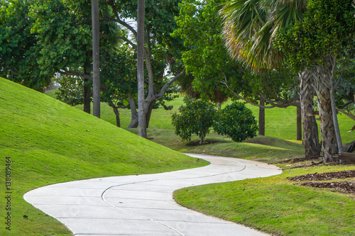 Fototapeta Naklejka Na Ścianę i Meble -  A winding, twisting path, trail or walkway in a public park in Miami Beach, Florida sits amongst palm trees on a sunny summer day
