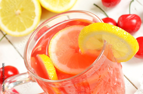 Fruit cherry ice tea with slice of lemon in mug and cherries