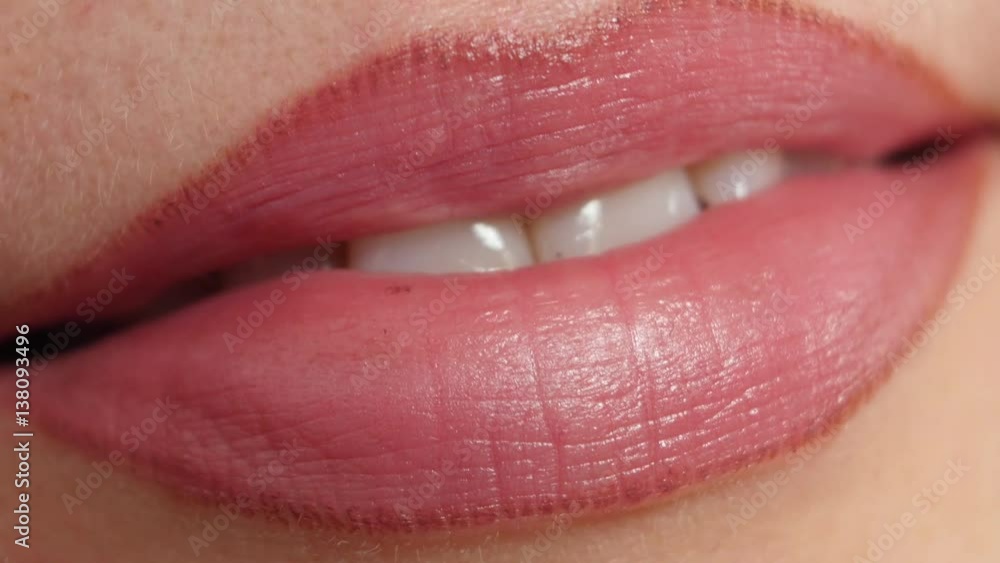 Close up of a beautiful toothy female smile with soft red lipstick on her lips and clean white teeth Close up of a beautiful toothy female smile with soft red lipstick on her lips and clean white teeth