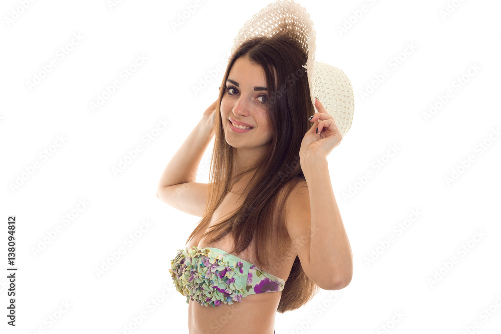 young cute brunette woman with big natural breasts in swimsuit with floral  pattern and straw hat smiling and looking at the camera isolated on white  background Stock Photo