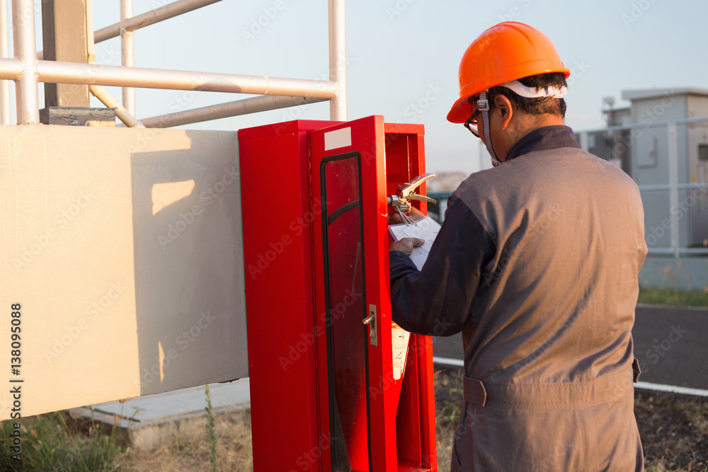 Fototapeta premium Safety officials checking a fire extinguisher