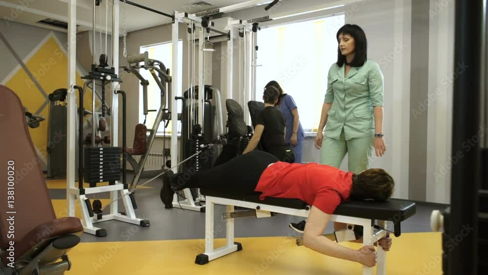 A group of people working out on training apparatus with individual instructors at gym. HD A group of people working out on training apparatus with individual instructors at gym. HD