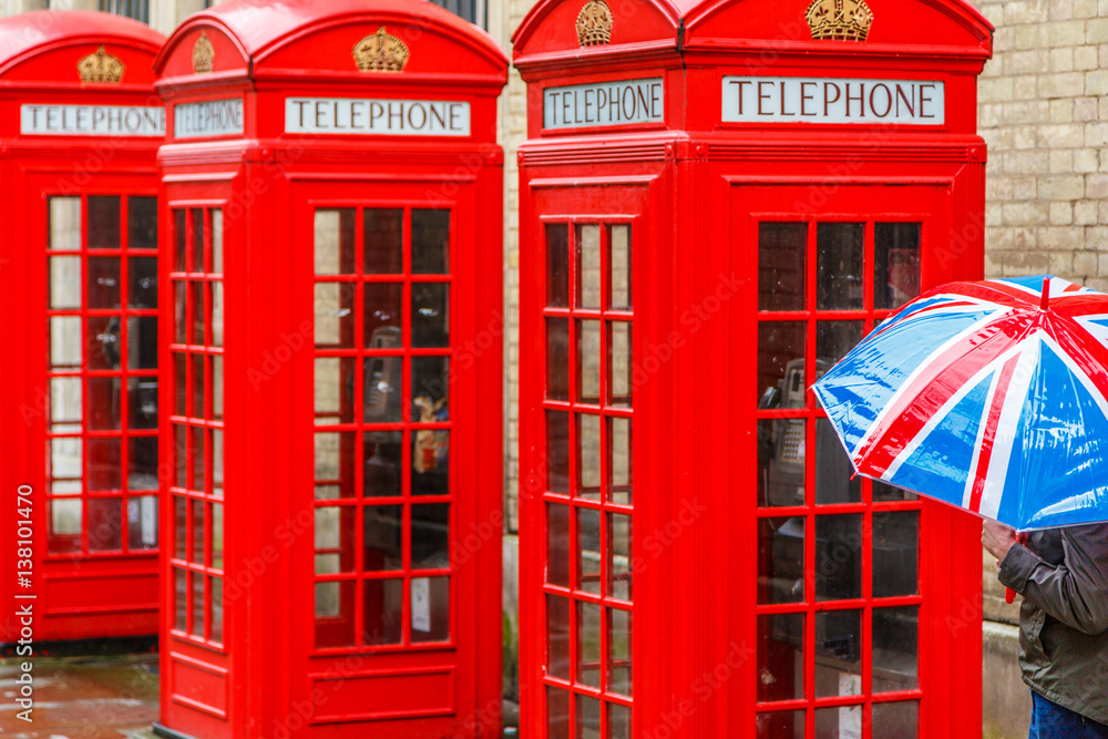 Three Red London Telephone Boxes, and Union flag Umbrella on a rainy day in London, England, UK Three Red London Telephone Boxes, and Union flag Umbrella on a rainy day in London, England, UK