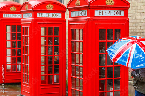 Three Red London Telephone Boxes, and Union flag Umbrella on a rainy day in London, England, UK