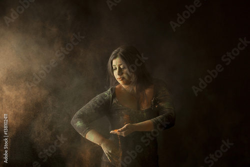 Indian woman throwing colored dust isolated on black background