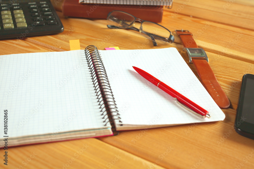 surface of a wooden table with notebook, smartphone, eye glasses, and pen surface of a wooden table with notebook, smartphone, eye glasses, and pen