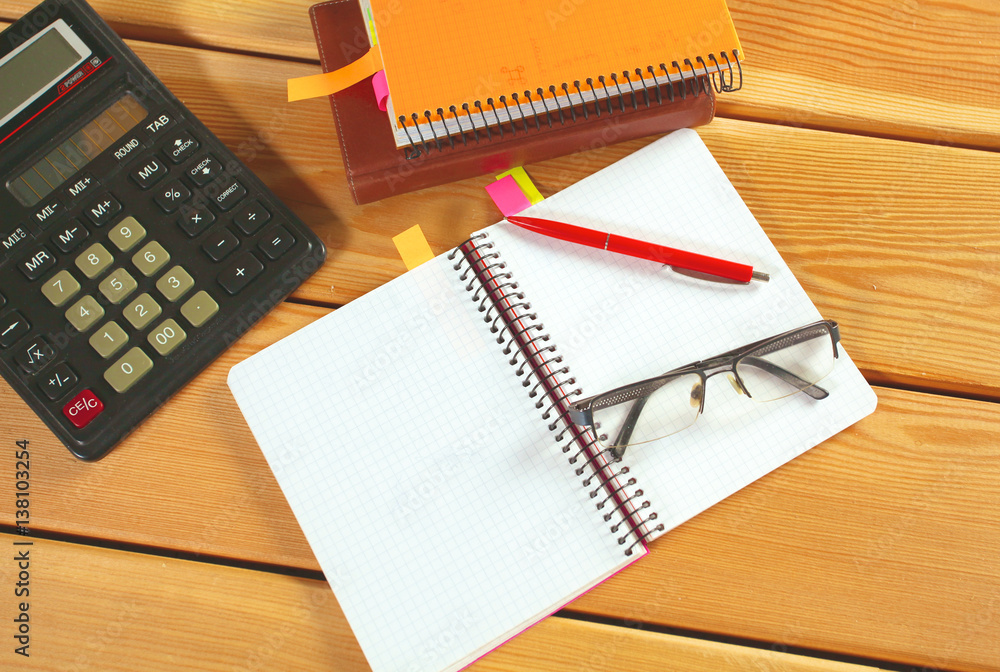 surface of a wooden table with notebook, smartphone, eye glasses, and pen surface of a wooden table with notebook, smartphone, eye glasses, and pen