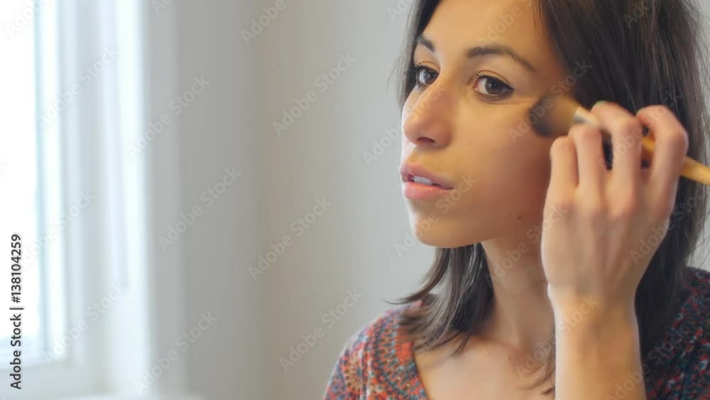 Stylish young woman applies makeup to face Stylish young woman applies makeup to face